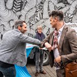 Helmuth Stöber von VOI fesch grüßt Künstler Jörg Rath mit einem Ellbogengruß